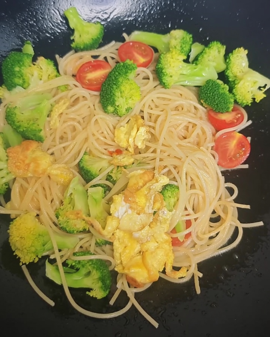 Preparato per insaporire cosparso sugli spaghetti e verdure nel wok.