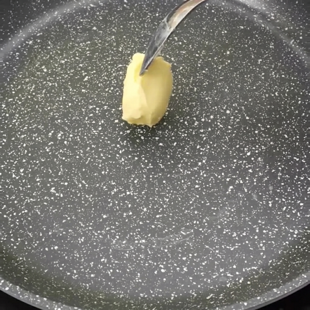 Una noce di burro che si scioglie in una padella antiaderente.