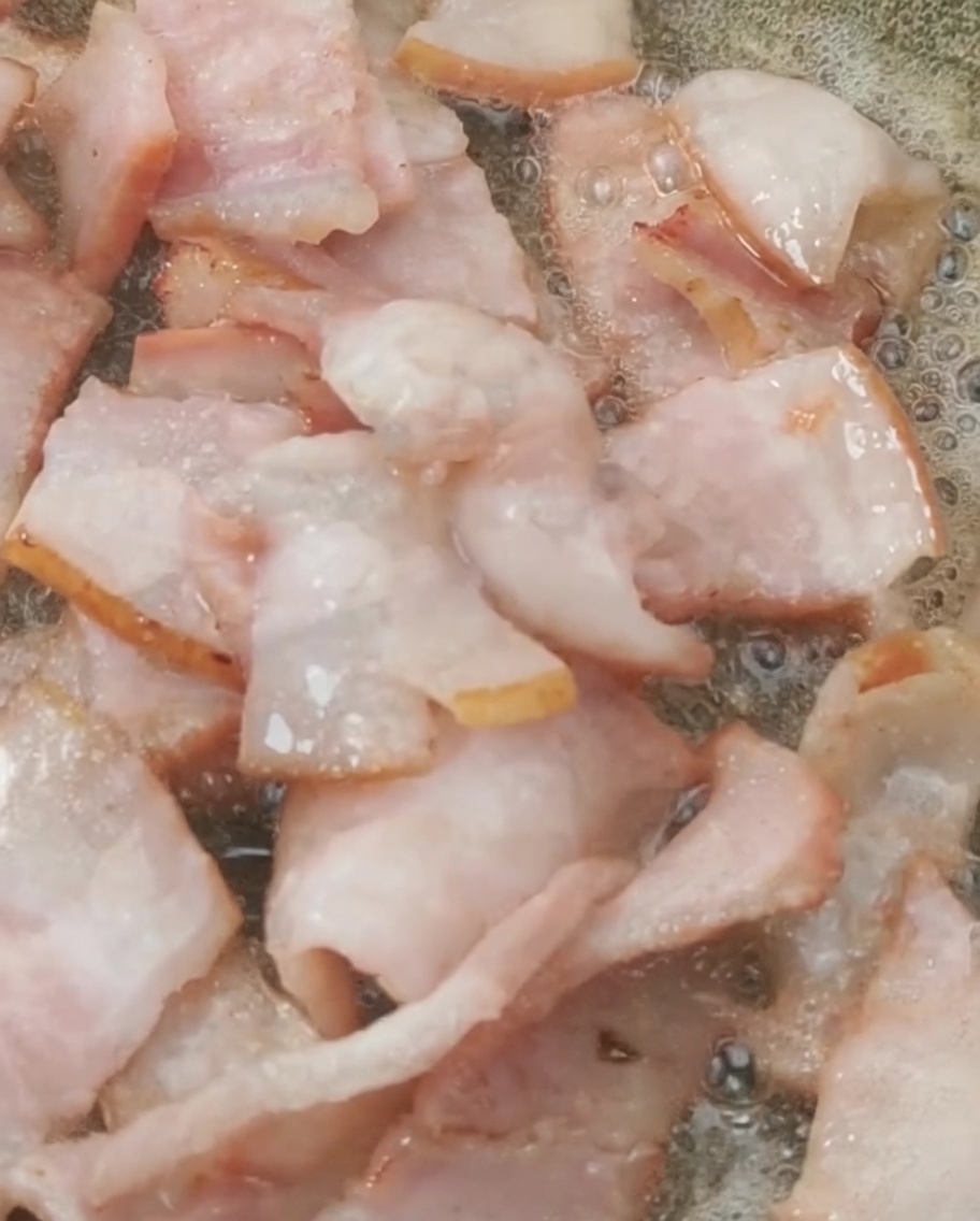 Pomodorini freschi aggiunti in padella con la pancetta dorata.