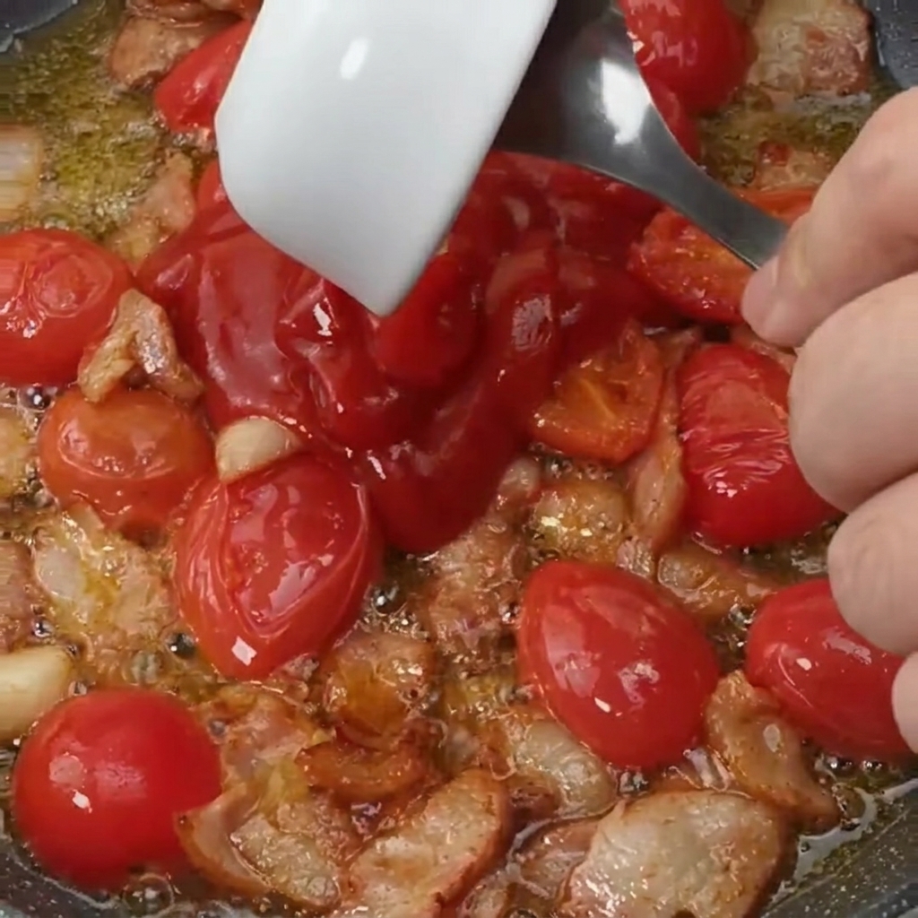 Salsa di pomodoro e zucchero aggiunti al composto di pancetta e pomodorini.
