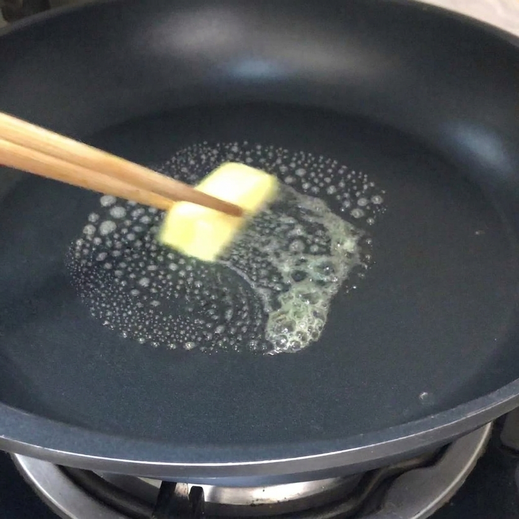 Una noce di burro che si scioglie in una padella calda.