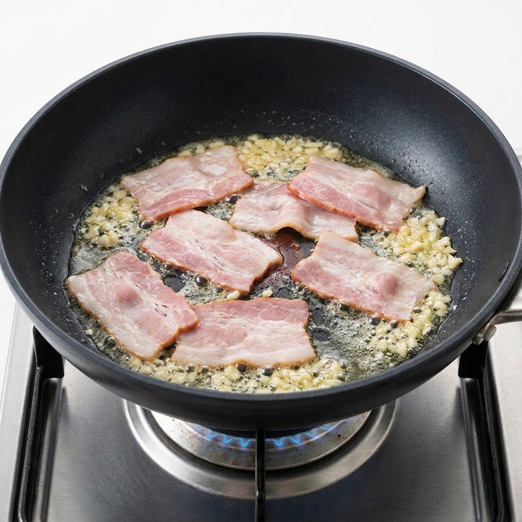 Pezzi di bacon che sfrigolano in una padella insieme allaglio tritato dorato e profumato.