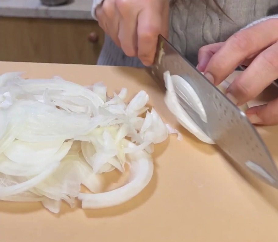Affettare finemente una cipolla dorata intera su un tagliere.