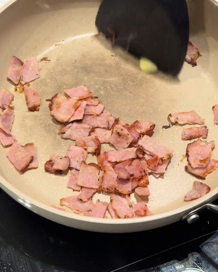 Cipolle bianche tritate che vengono mescolate nella padella con pancetta e burro.