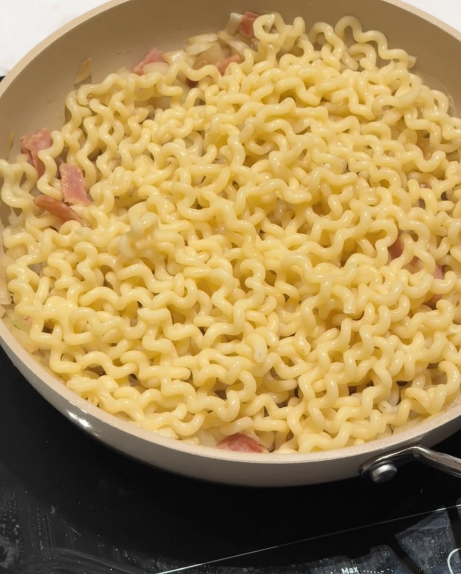 Latte parzialmente scremato versato sopra la pasta nella padella.