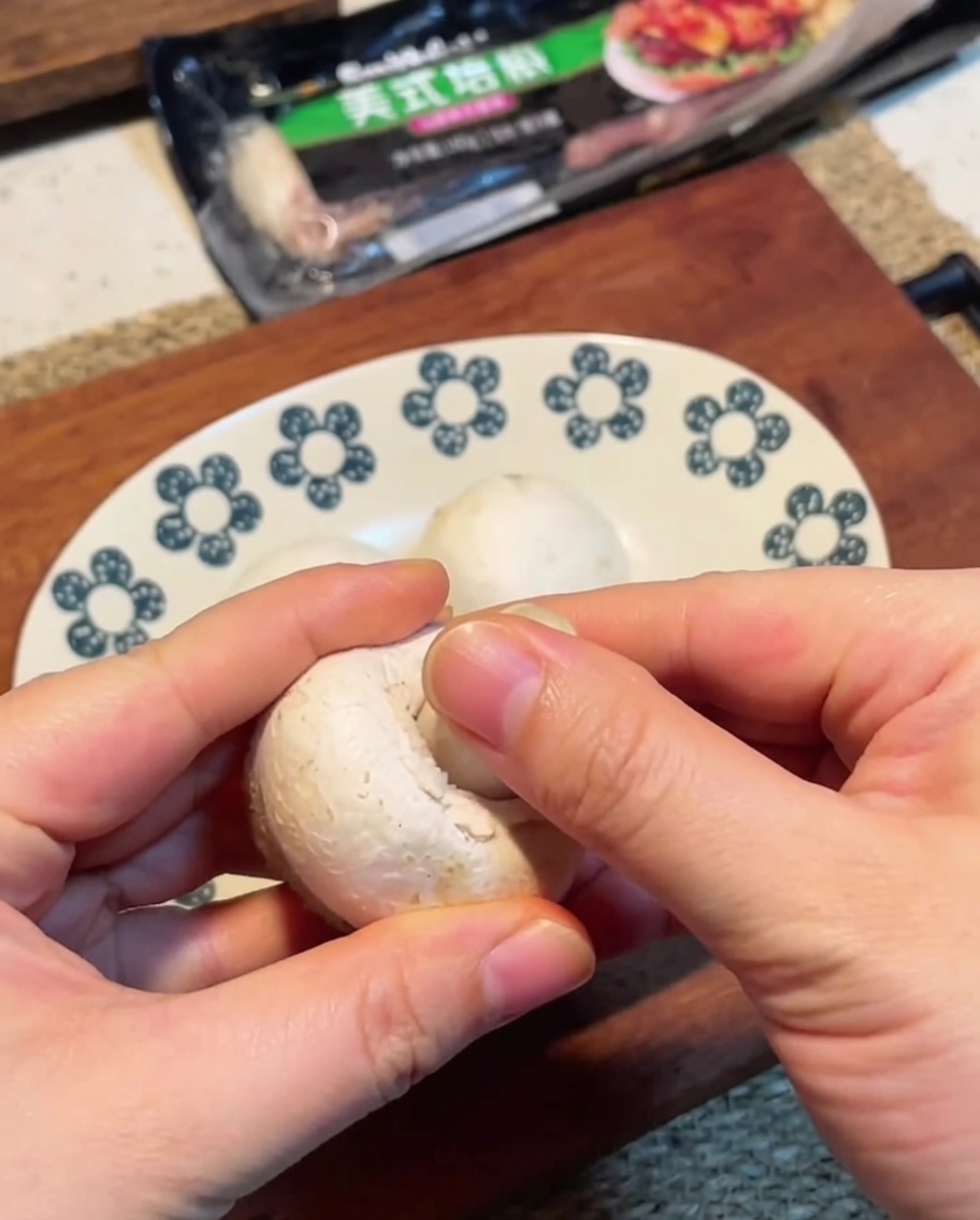 Funghi champignon affettati finemente su un tagliere in legno.