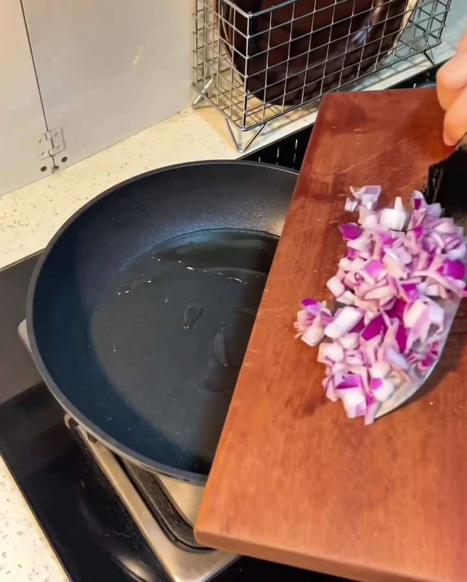 Bacon e cipolla che sfrigolano in padella con il burro fuso.