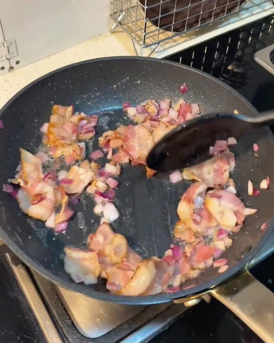 Funghi affettati mescolati in padella con bacon e cipolla.