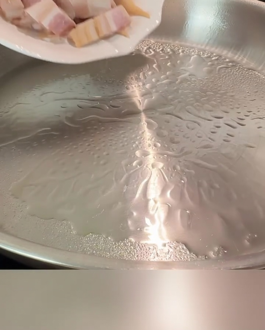 Pezzetti di pancetta che sfrigolano in una padella calda fino a diventare dorati e croccanti.