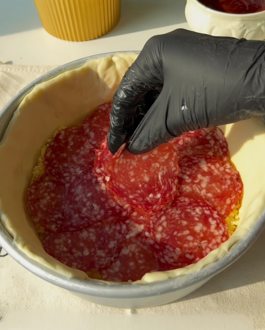 Strisce di pancetta posizionate sopra lo strato di salame.