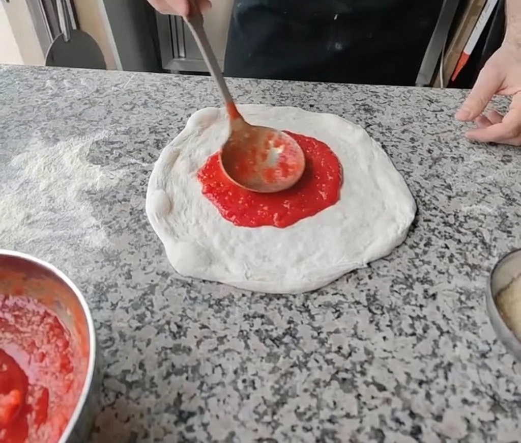 Stendere la salsa di pomodoro rosso brillante al centro dellimpasto steso con un mestolo.