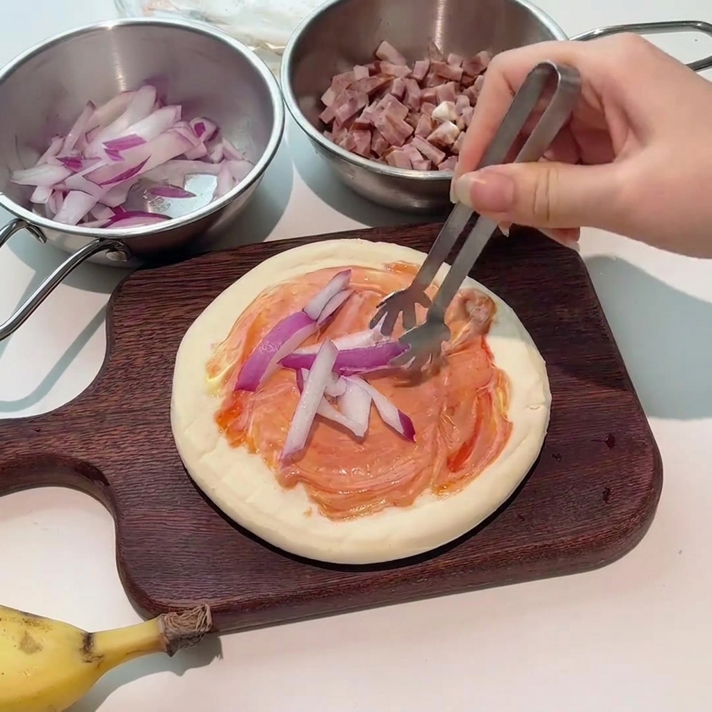 Pinze che posizionano fette di cipolla rossa fresca sulla base della pizza condita.