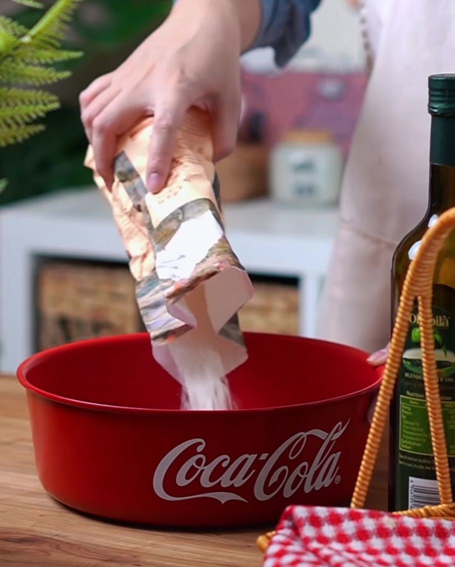 Primo piano di farina, lievito e sale versati in una ciotola rossa Coca-Cola.