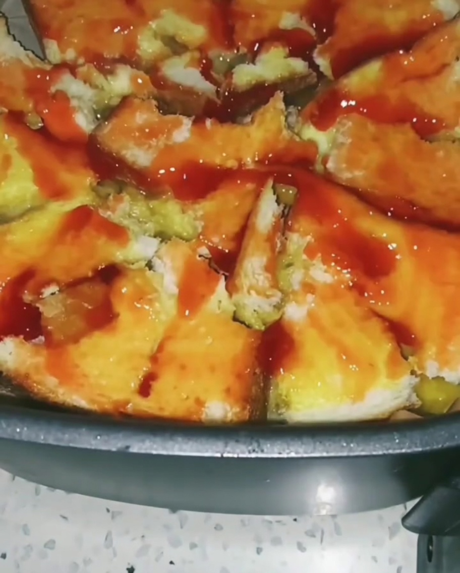 Verdure miste colorate come mais e piselli sparse sopra la base di toast ricoperta di salsa di pomodoro.