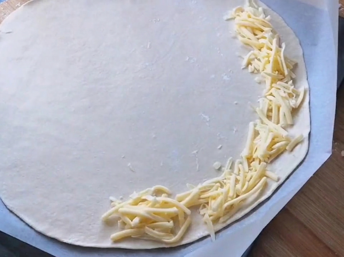 La salsa bianca viene spalmata su una base per pizza rotonda.