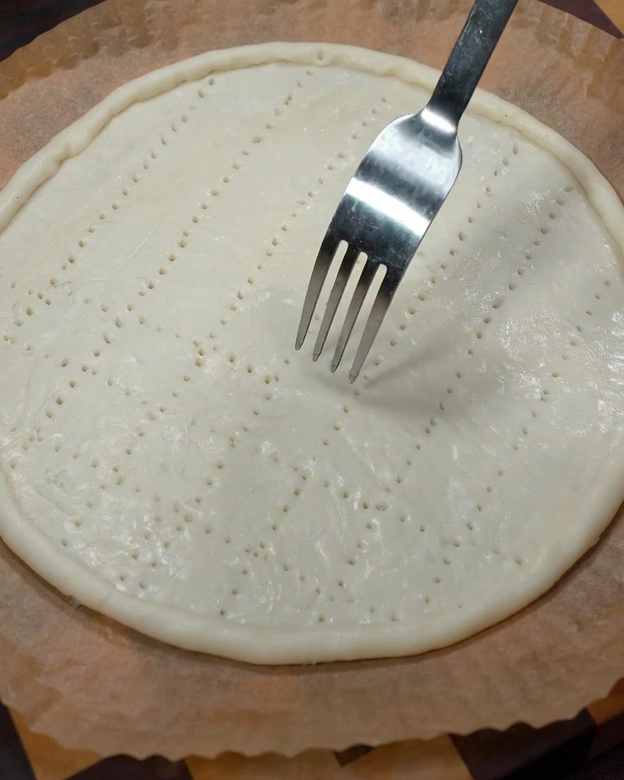 Una forchetta di metallo che preme sulla base dellimpasto creando fori uniformi.