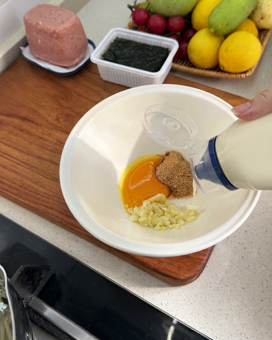 Un flacone di maionese che aggiunge una piccola quantità di salsa nella ciotola con gli altri ingredienti.