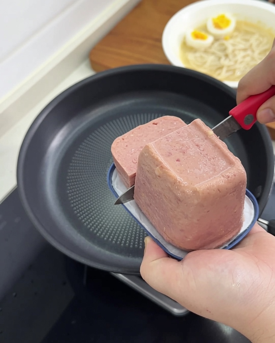 Fette di carne in scatola che friggono in una padella antiaderente fino a raggiungere un colore dorato.