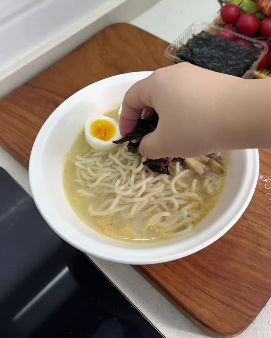Una ciotola di ramen guarnita con metà di uovo sodo, funghi, germogli di bambù e un pezzo di alga nori.