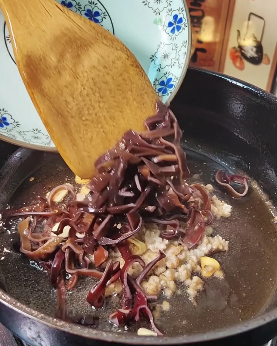Carne macinata e funghi orecchie di legno saltati in padella con una spatola.