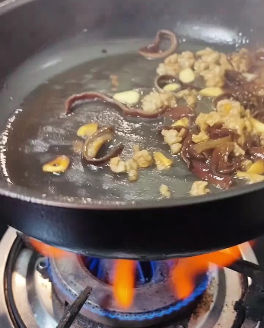 Salsa di soia e salsa di ostriche versate nella padella con carne e funghi.