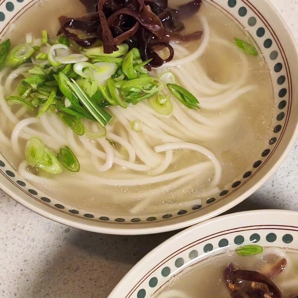 Una ciotola di ramen guarnita con carne saltata, funghi e cipollotti.