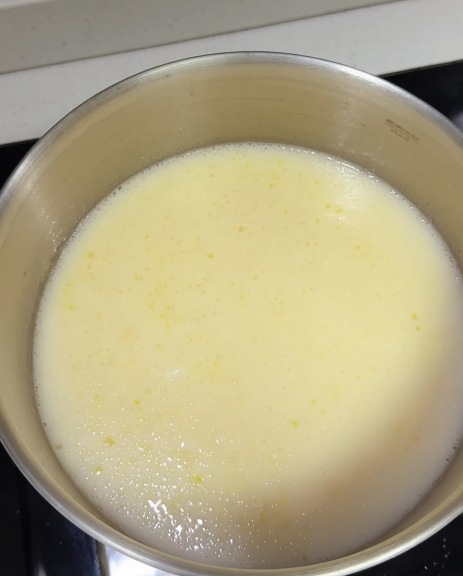 Noodles ramen cotti aggiunti in una pentola di brodo tonkotsu cremoso bollente.