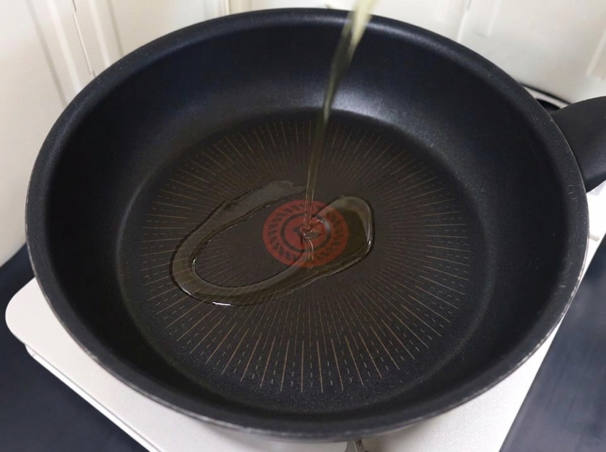 Fettine sottili di maiale che rosolano in padella con olio caldo.