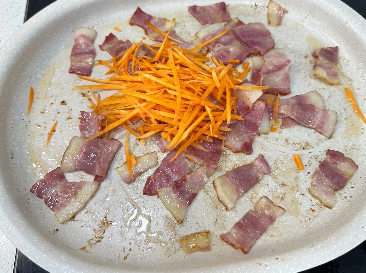 Un mix di carote, cipolle, cavolo e germogli di soia aggiunti in padella con la pancetta.