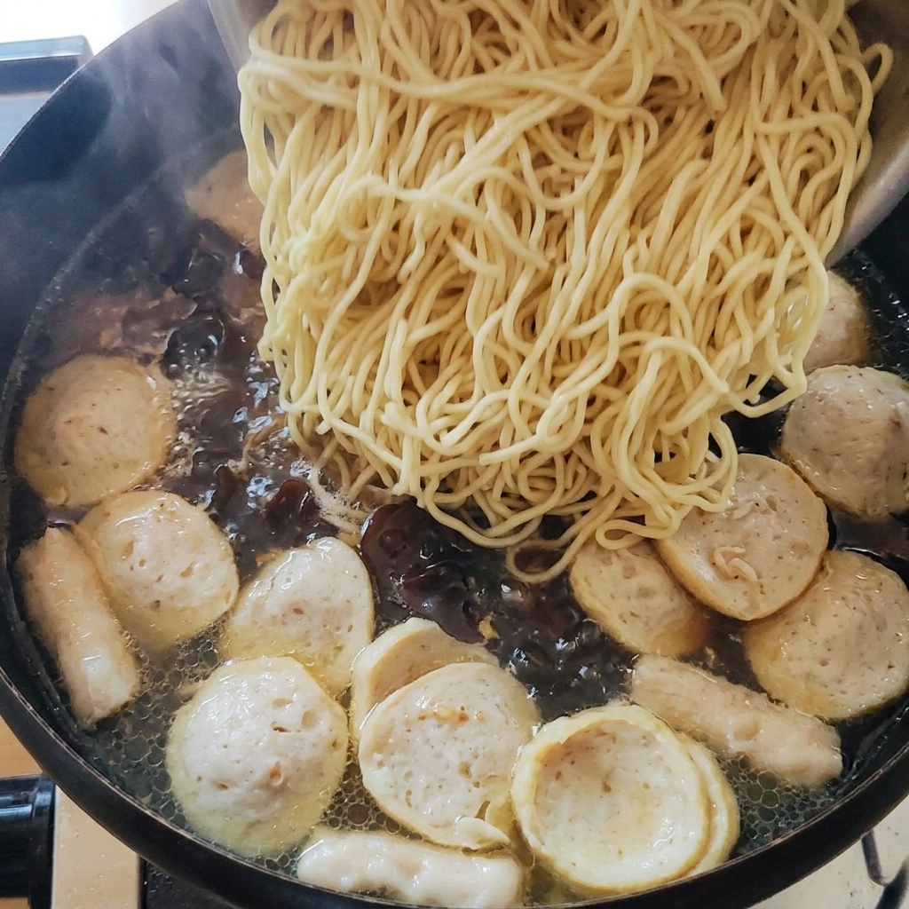 Noodle cotti aggiunti alla pentola della zuppa.