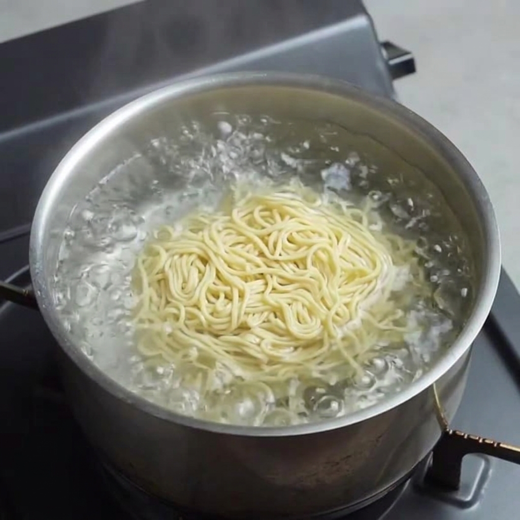 Noodles freschi gialli che cuociono in acqua bollente.