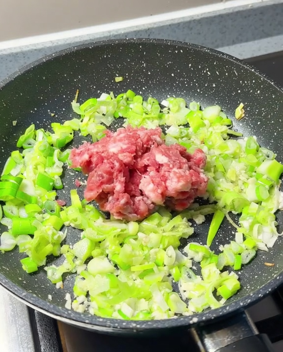 Carne macinata fresca aggiunta al centro della padella con aromi.