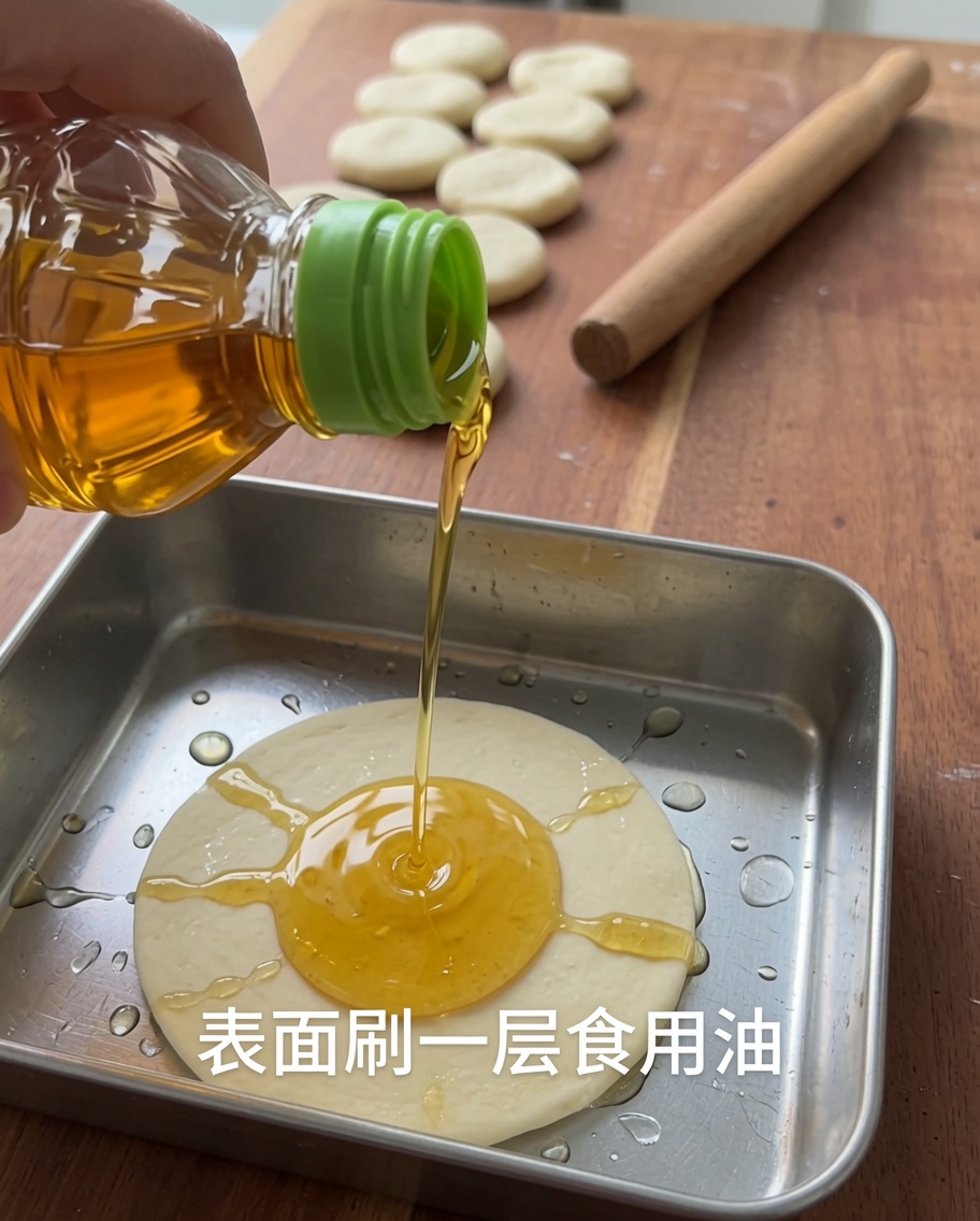Olio versato su un pezzo di impasto in un contenitore metallico.