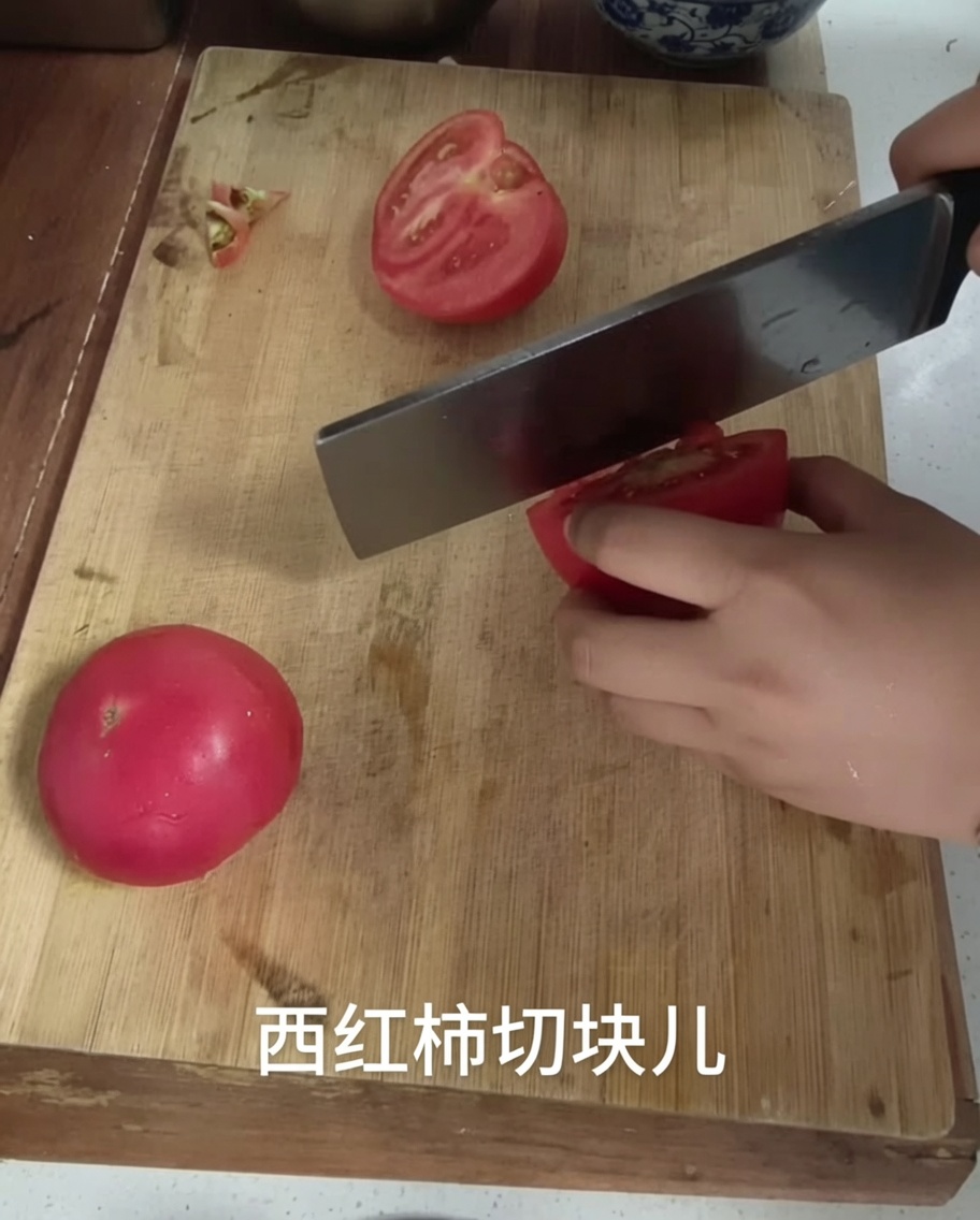 Coltello da cucina che taglia un pomodoro a cubetti su un tagliere.