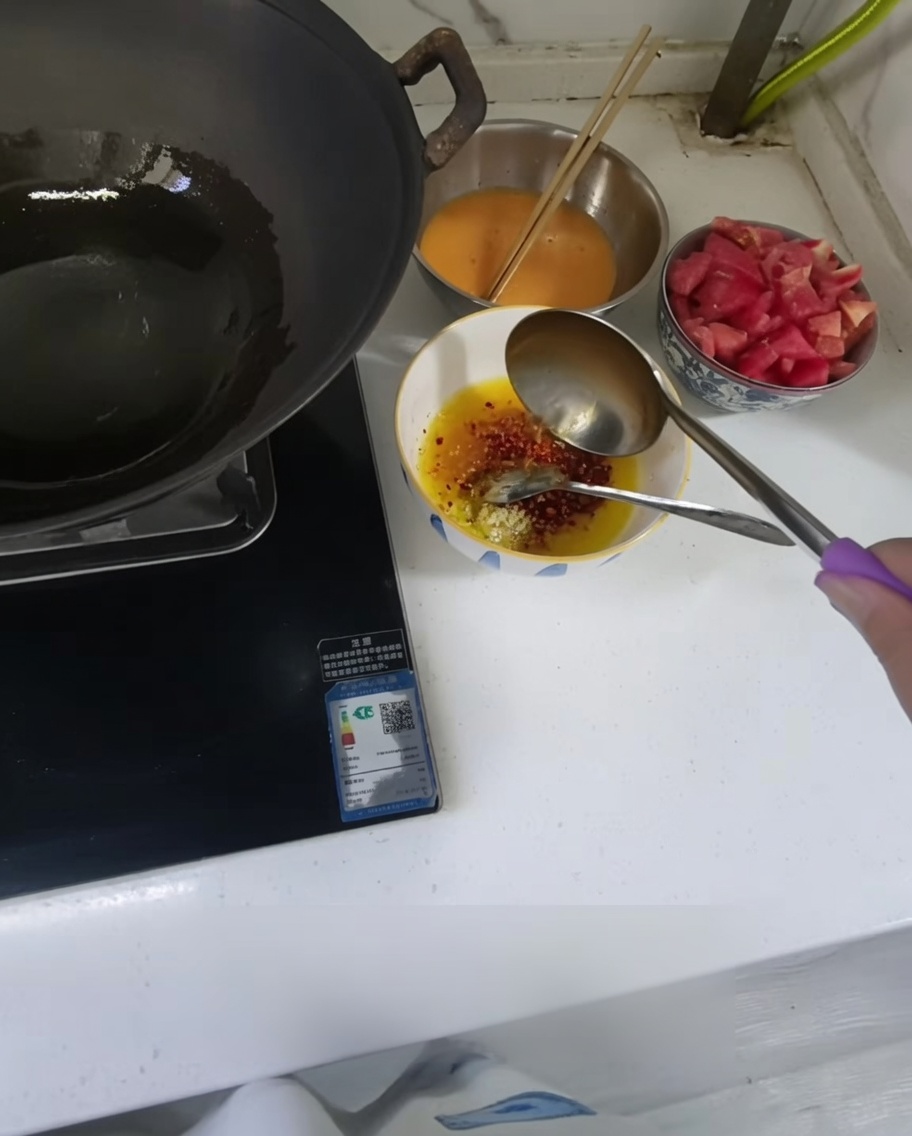 Olio caldo versato da un mestolo in una ciotola con aglio tritato e peperoncino.
