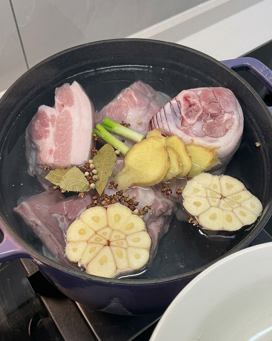 Carne di maiale nella pentola con aggiunta di cipolla, aglio, zenzero, cipollotti e spezie intere.