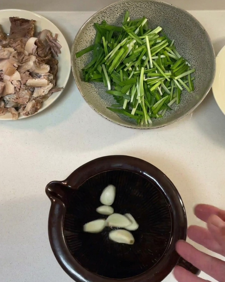 Spicchi daglio pestati in una pasta allinterno di un mortaio in ceramica scura.