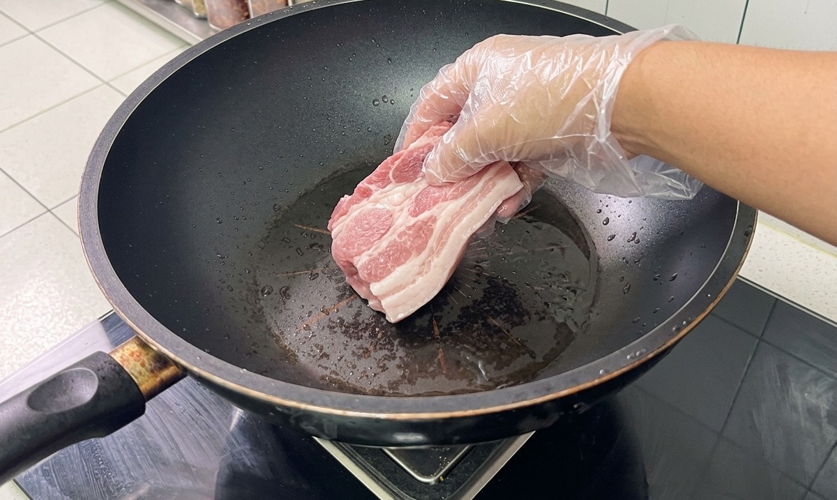 Ossa e pancetta di maiale in un wok dacqua con aromi durante la sbollentatura.