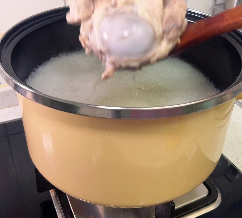 Carne sfilacciata dalle ossa di maiale cotte indossando guanti protettivi.