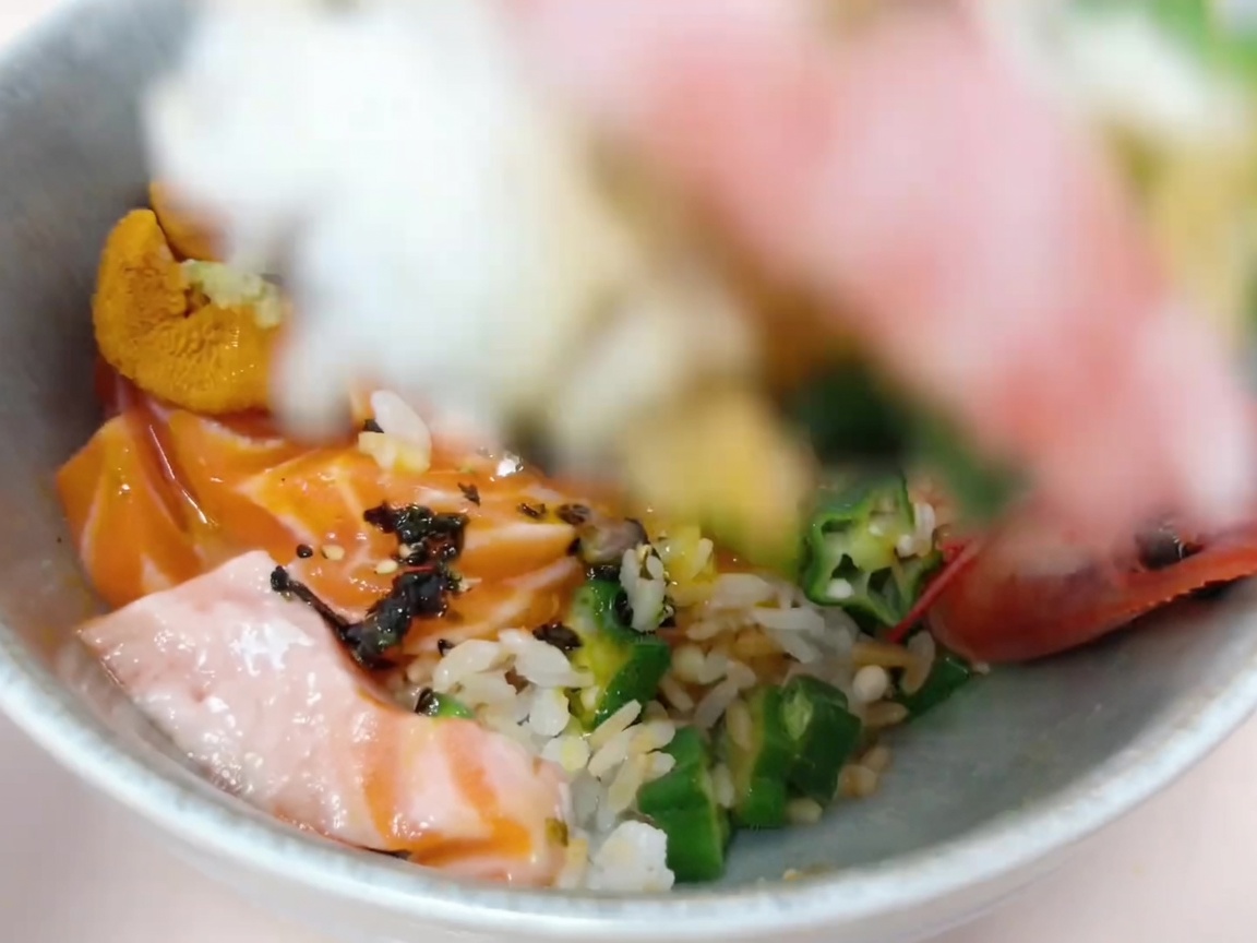 Ingredienti disposti con cura sopra il riso per creare la base del donburi.