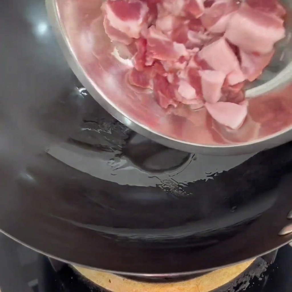 Fette di pancetta aggiunte in un wok caldo con un filo dolio.