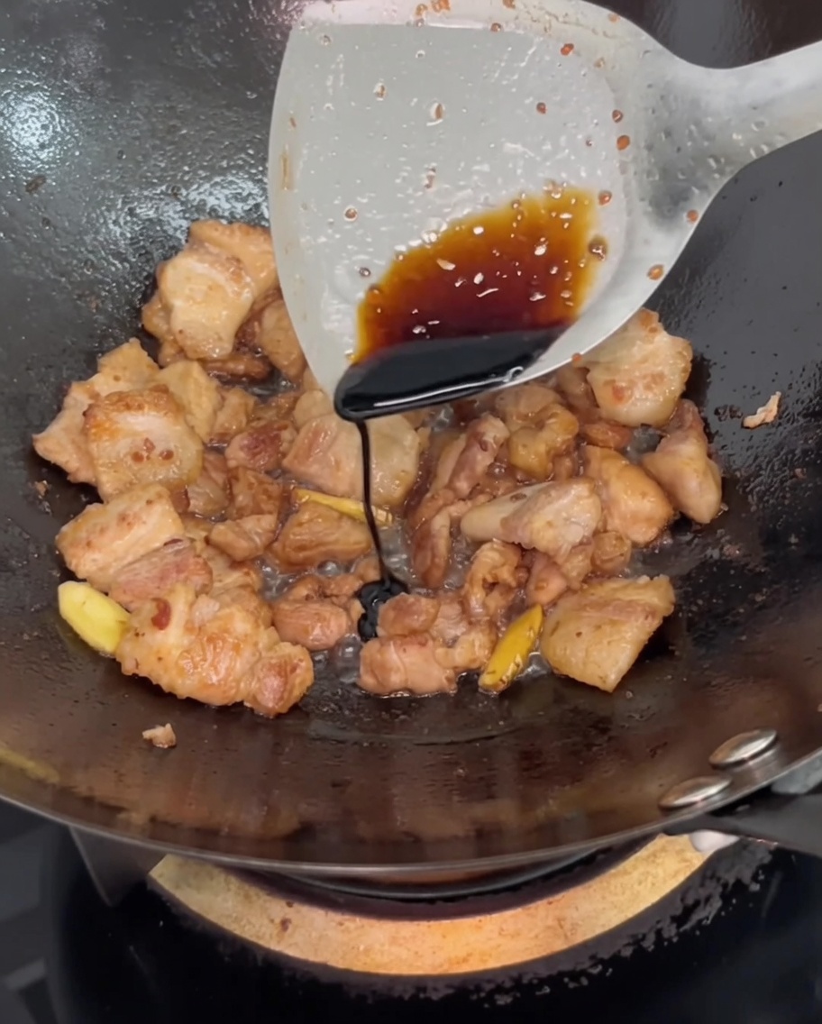 Salsa di soia scura versata sulla carne nel wok per regolare il colore.