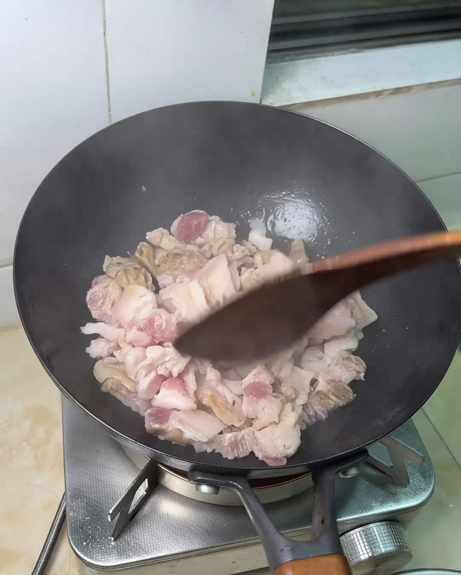 Fettine di pancetta cruda che friggono in una padella calda.