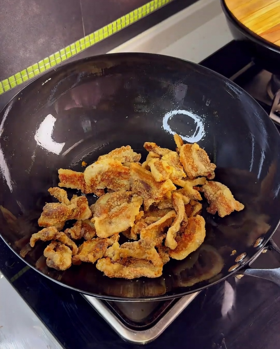 Pancetta fritta croccante in un wok saltata con aglio e salsa a base di soia.