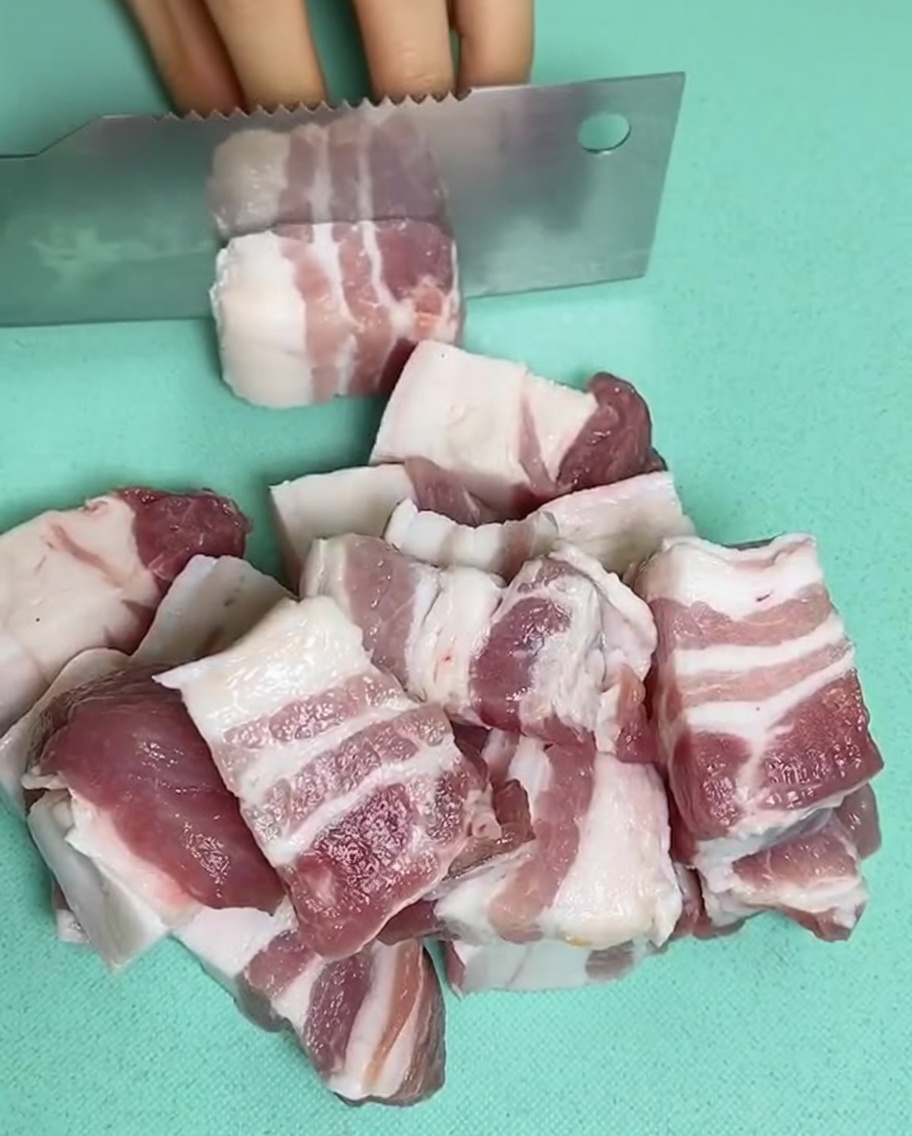 Pezzi di pancetta cruda in una pentola piena di acqua fredda, zenzero e vino da cucina.