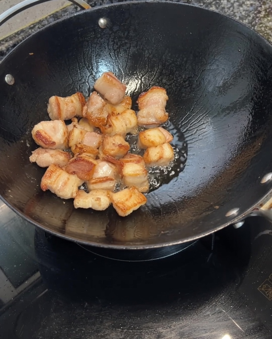 Spicchi daglio aggiunti al wok con la pancetta rosolata.