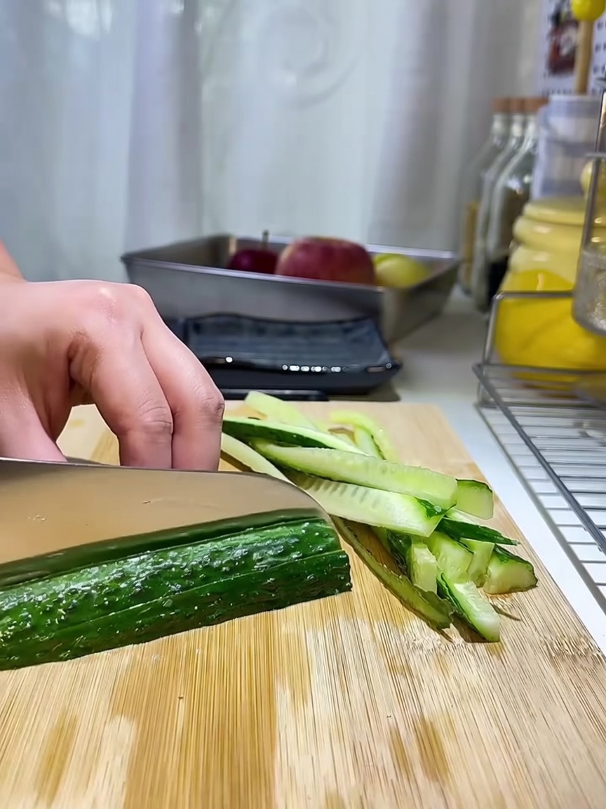 Strisce sottili di cetriolo disposte ordinatamente su un tagliere di legno.