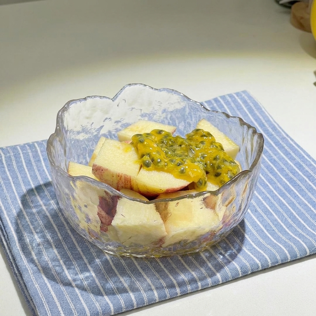 Ciotola di vetro con cubetti di mela rossa conditi con polpa di frutto della passione e miele.