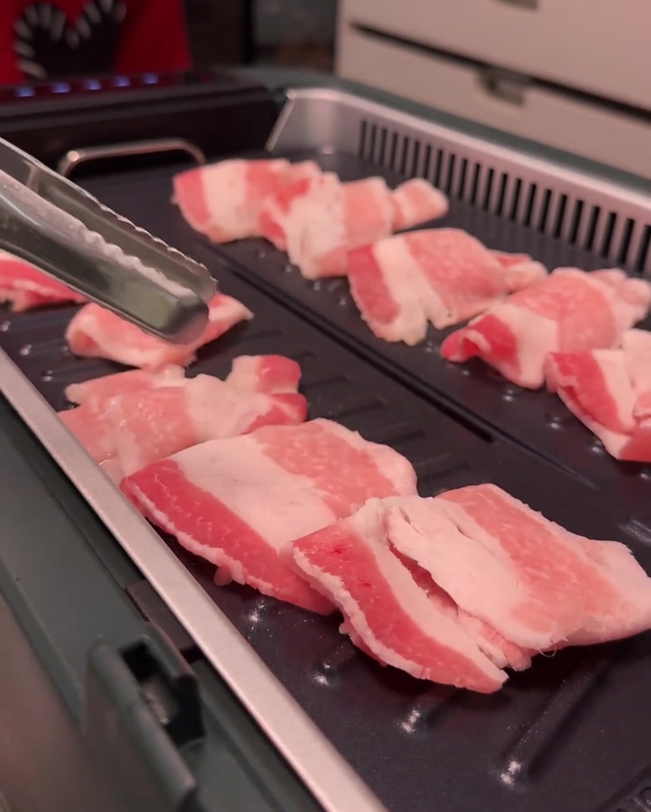 Fettine di pancetta che rosolano sulla piastra elettrica.