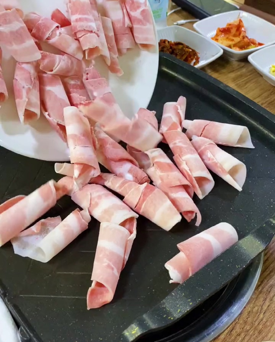 Fettine di pancetta cruda posizionate su una piastra calda.